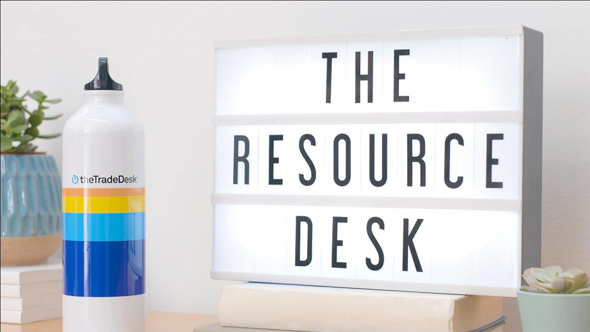Image of a board displaying "The Resource Desk" with a water bottle with The Trade Desk logo, to the left