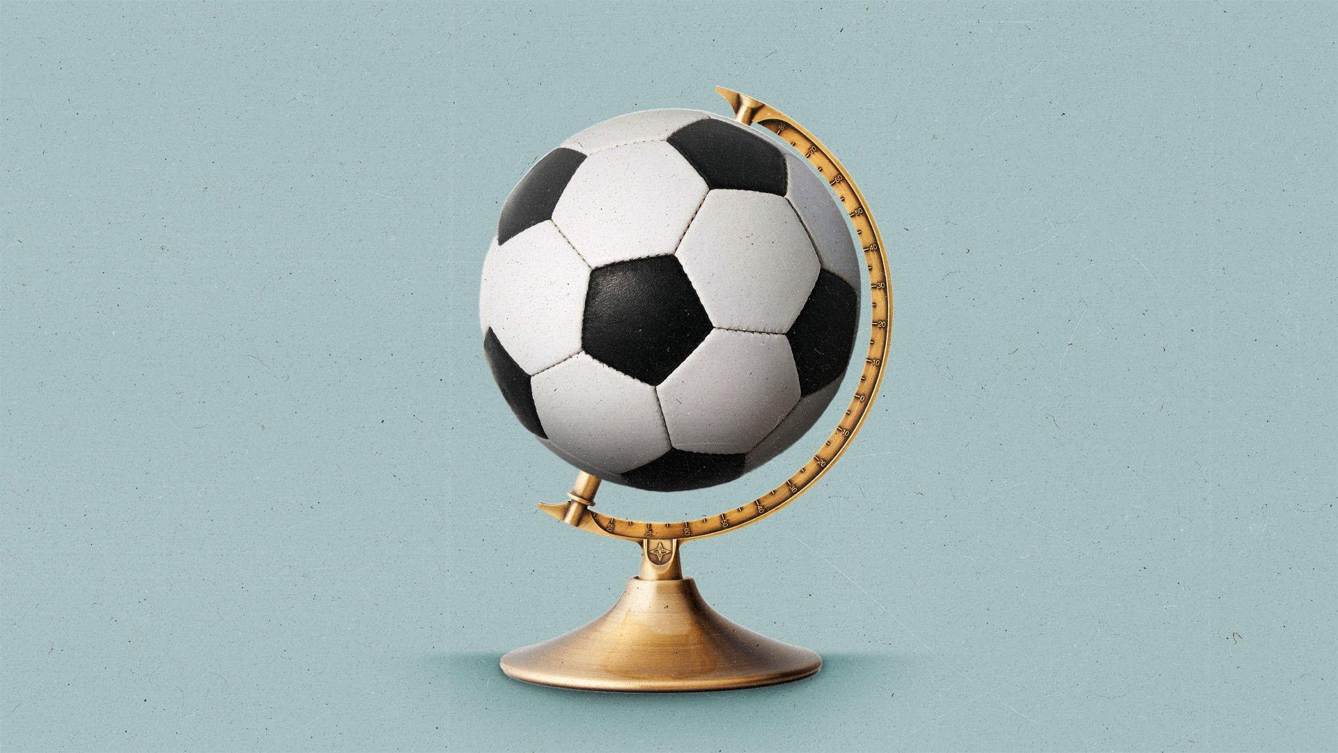 A soccer ball sits on a brass globe stand.