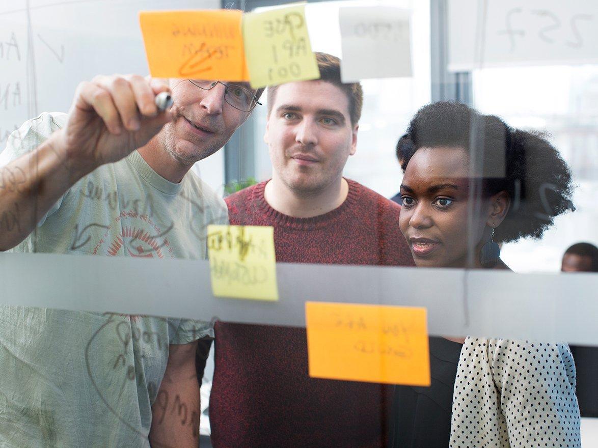 Three coworkers in a brainstorming session with post-it notes